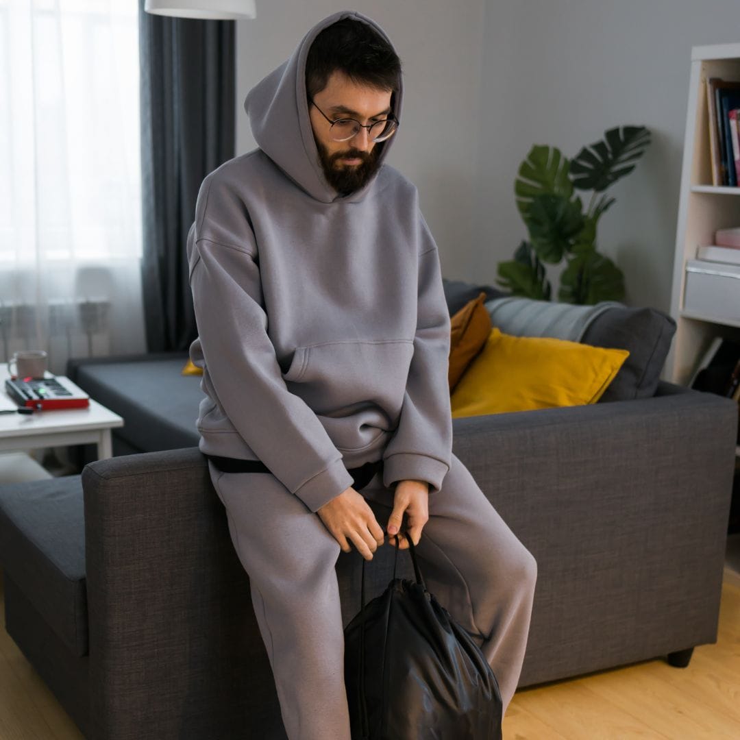 a man in a sweatsuit sitting defeated on a couch