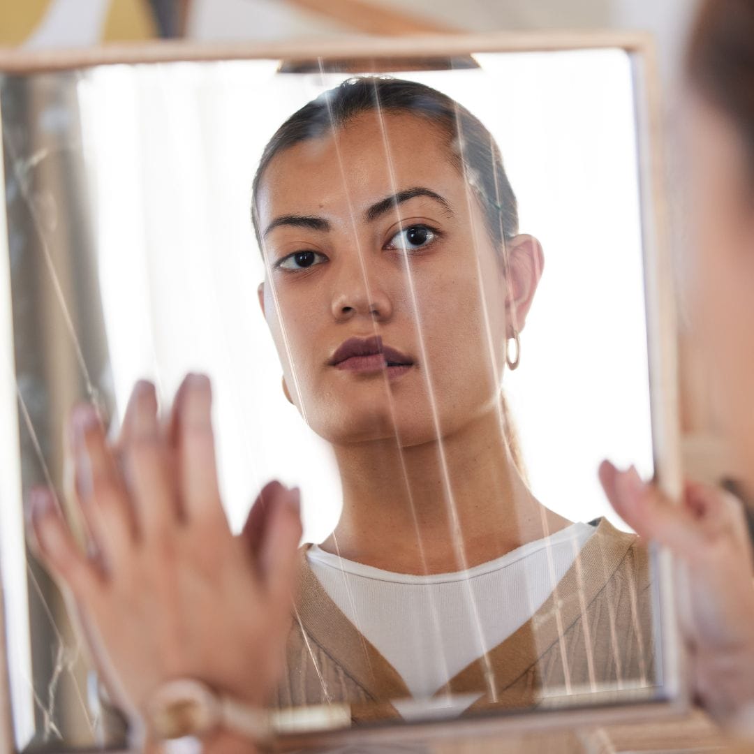 person looking at reflection in distorted mirror